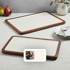 two wooden serving trays with white plates and silverware next to each other on a table