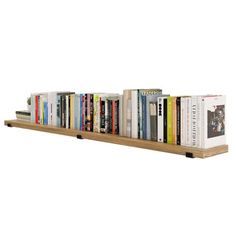 a bookshelf filled with lots of books on top of each other in front of a white wall