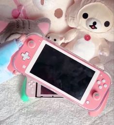 a pink nintendo wii game controller sitting next to stuffed animals on a white bed sheet