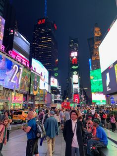 a man standing in the middle of a busy city at night with lots of people