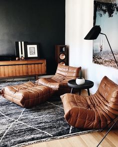 a living room with black walls and leather furniture