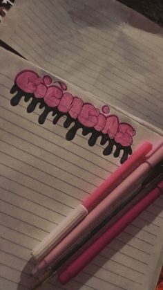 two pink pens sitting on top of a piece of lined paper next to each other