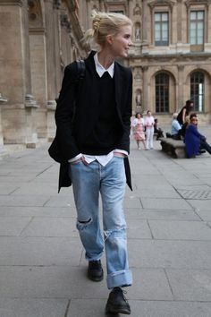 a woman walking down the street in jeans and a black jacket with white shirt on