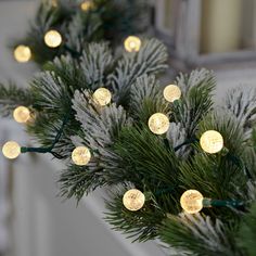 christmas lights are hanging from the branches of a pine tree