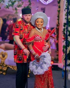 a man and woman dressed in red posing for the camera with an elaborate costume on