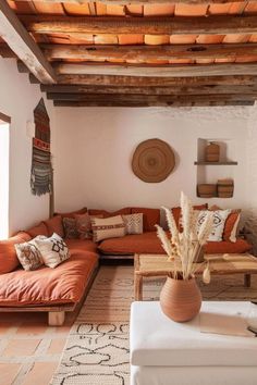 a living room filled with lots of furniture next to a wooden beamed ceiling over a window