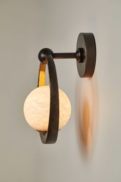 a wall light with a circular glass shade hanging from it's arm and two lights on each side