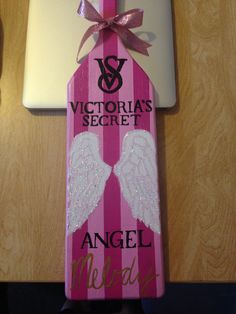 a pink and white sign with angel wings on it next to a laptop computer that says victoria's secret