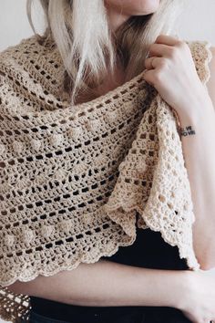 a woman with blonde hair wearing a crocheted shawl