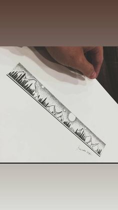 a pencil drawing of trees and mountains on white paper with hand holding it over the edge