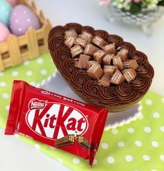 a kitkat chocolate cake next to a candy bar on a table with easter eggs in the background