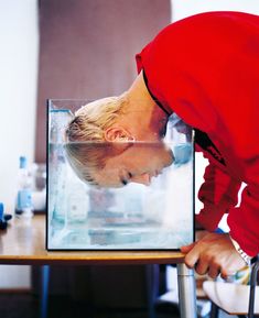 a woman bending over to look at something in a glass box