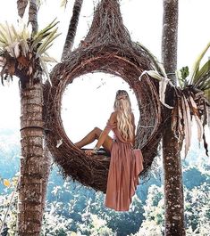 a woman sitting in a bird nest with palm trees around her and the words bali, indonesia on it