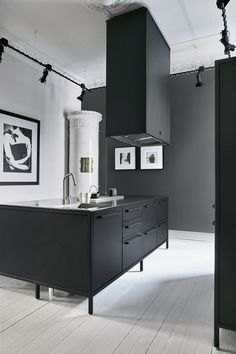 a black and white kitchen with an island in front of the stove, sink and cabinets