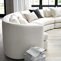 a large white couch sitting in a living room next to a tall window with lots of windows