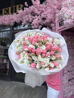 a bouquet of pink and white flowers in front of a store