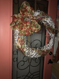 a wreath hanging on the front door of a house with chains and bows attached to it