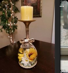 a glass vase with flowers in it and a candle on the table next to it