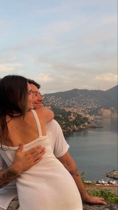 a man and woman hugging each other on top of a hill