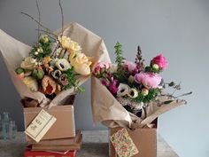 two boxes with flowers in them sitting on a table