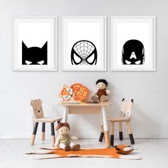 three children's artwork pieces on the wall above a table with toys and stuffed animals