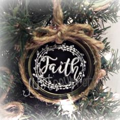 a christmas ornament with the word faith on it hanging from a pine tree