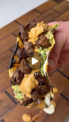 someone is holding up a taco filled with meat and guacamole sauce