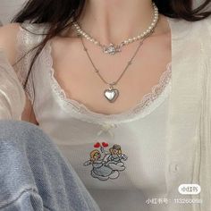 a woman wearing a white shirt and necklace with two angels on it's chest