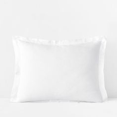 a white pillow on a bed next to a wall