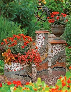 three pots with flowers in them sitting on the ground next to some bushes and trees