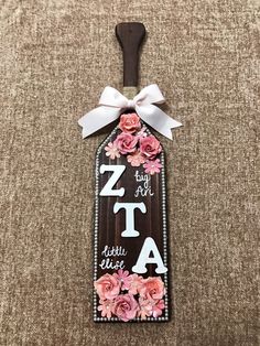 a wooden sign with flowers on it that says zita and has a white bow