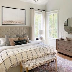 a bedroom with a bed, dresser and mirror in the corner next to a window