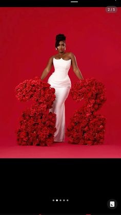 a woman in a white dress is standing next to red flowers with the number 20 on it