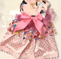 a dress made out of pink and gold sequins with a bow on the front