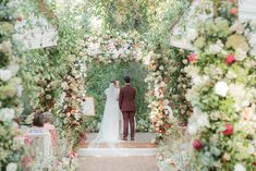 the bride and groom are getting married under an arch of flowers