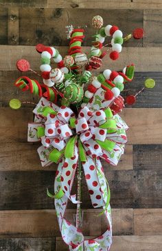 a green and white bow with candy canes attached to the front of a wooden wall