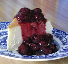 a piece of cheesecake on a blue and white plate with cherries in it