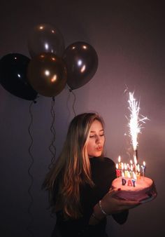 a woman holding a birthday cake with lit candles