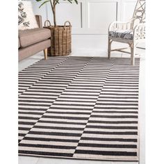 a black and white area rug in a living room with a couch, chair and potted plant