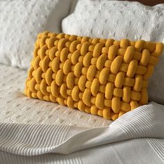 a yellow pillow is sitting on a white bed