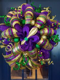 a purple and green christmas wreath with bells on the front door, decorated with ornaments