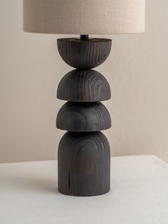 a lamp sitting on top of a table next to a white wall with a beige shade