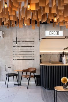 the interior of a coffee shop with wooden chairs and lights hanging from the ceiling above