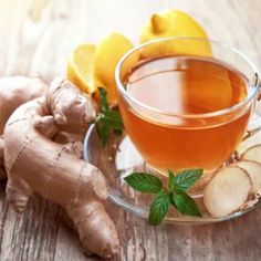 a glass cup filled with tea next to sliced lemons and ginger