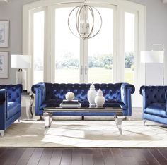 a living room filled with blue couches and white tables in front of a large window