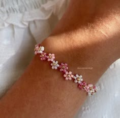 a close up of a person's arm wearing a bracelet with flowers on it