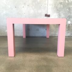 a pink table sitting on top of a cement floor