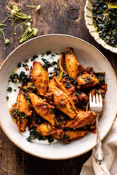 a white bowl filled with chicken and spinach on top of a wooden table next to a