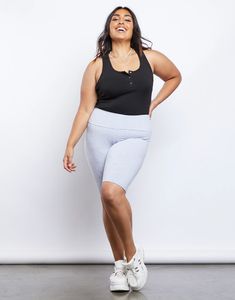 a woman is smiling while standing in front of a white wall with her hands on her hips