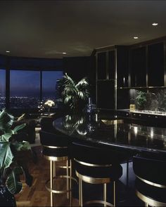 a kitchen with black counter tops and gold stools in front of a large window